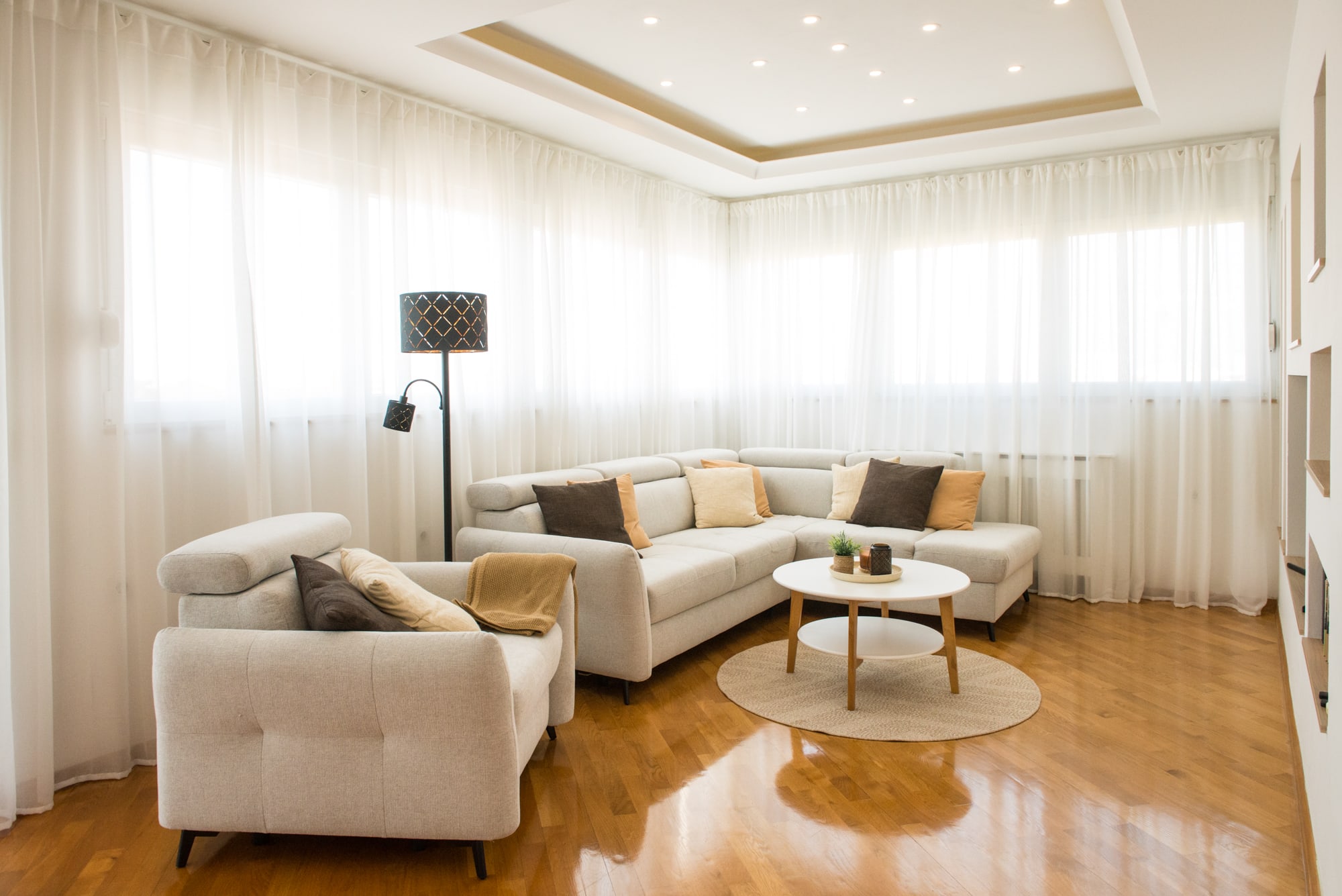 Bright living room with a large corner sofa, armchair and wraparound windows