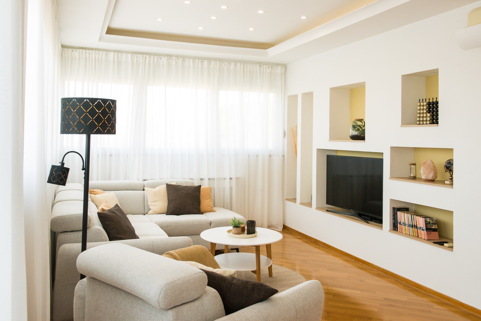 Living room with corner sofa, armchair and an illuminated built-in television wall