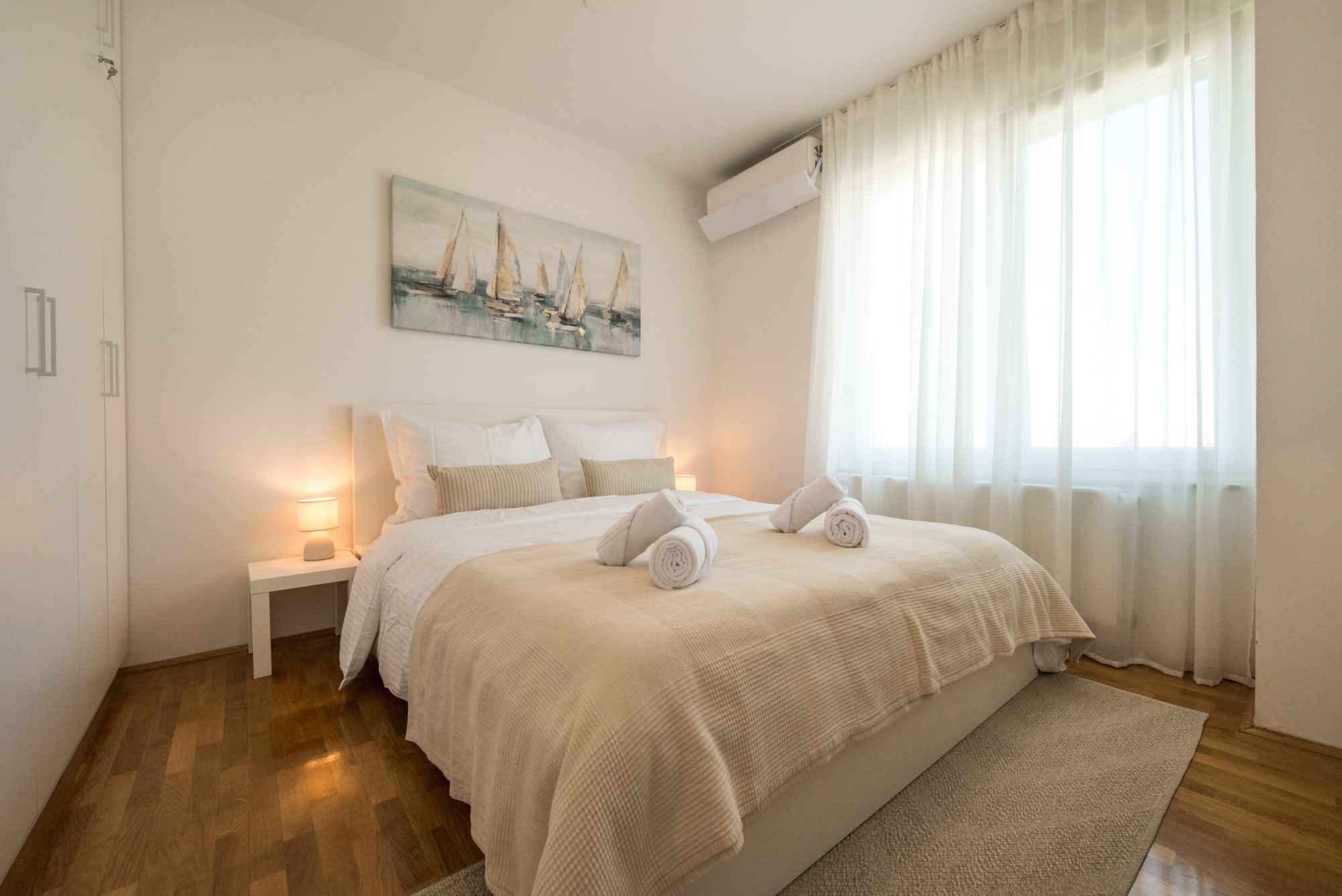 Main bedroom with a large bed, fresh towels, built-in wardrobes and natural light